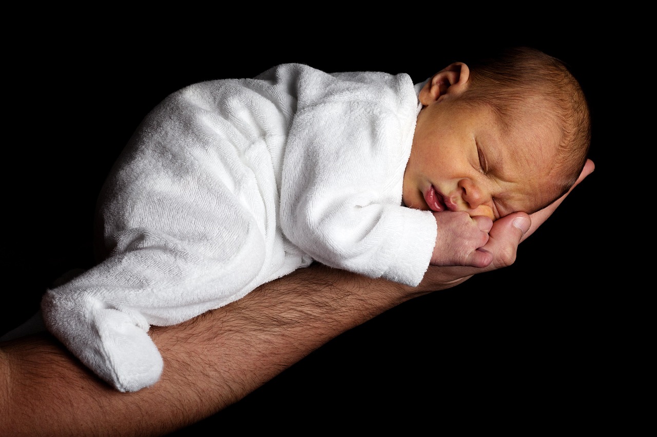 Adult hands symboliging the Good Hands God holding and protecting a small baby.