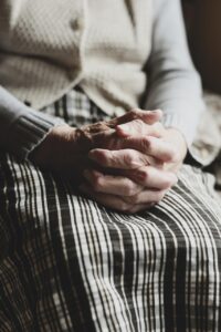 elderly hands clasped in prayer with soft sunset background, symbolizing last day reflections