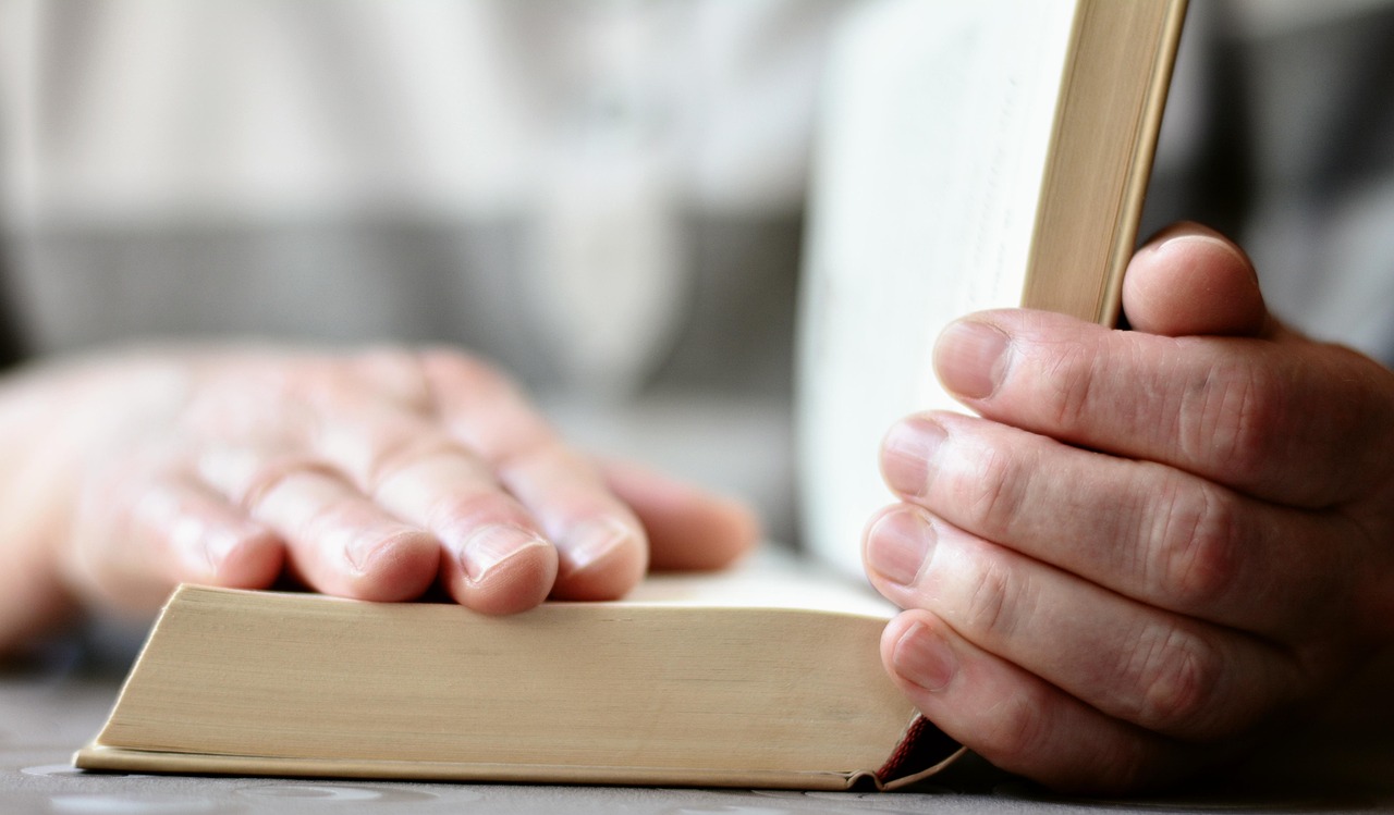 Open Bible with hands in worship indicating loving God