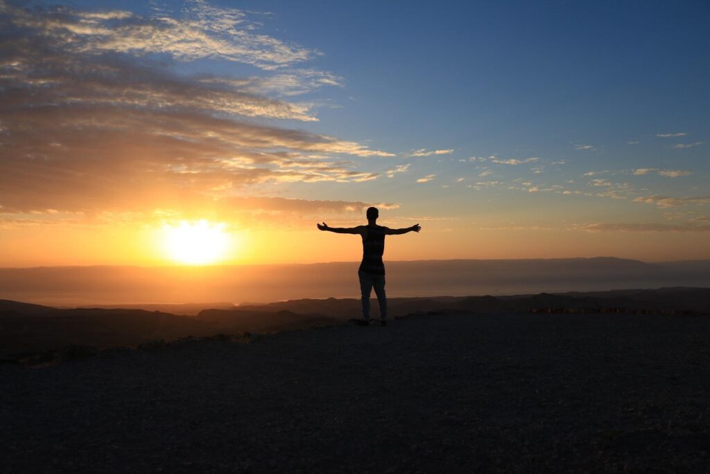 Open arms lifted in surrender to God at sunrise