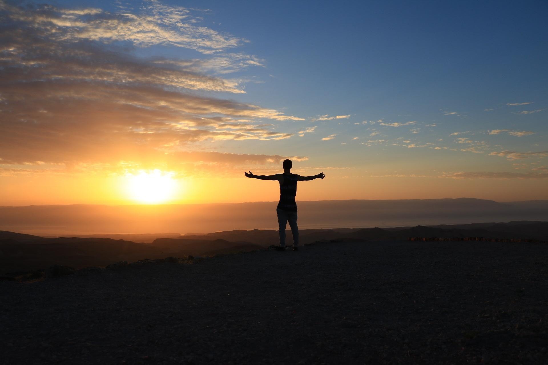 Open arms lifted in surrender to God at sunrise