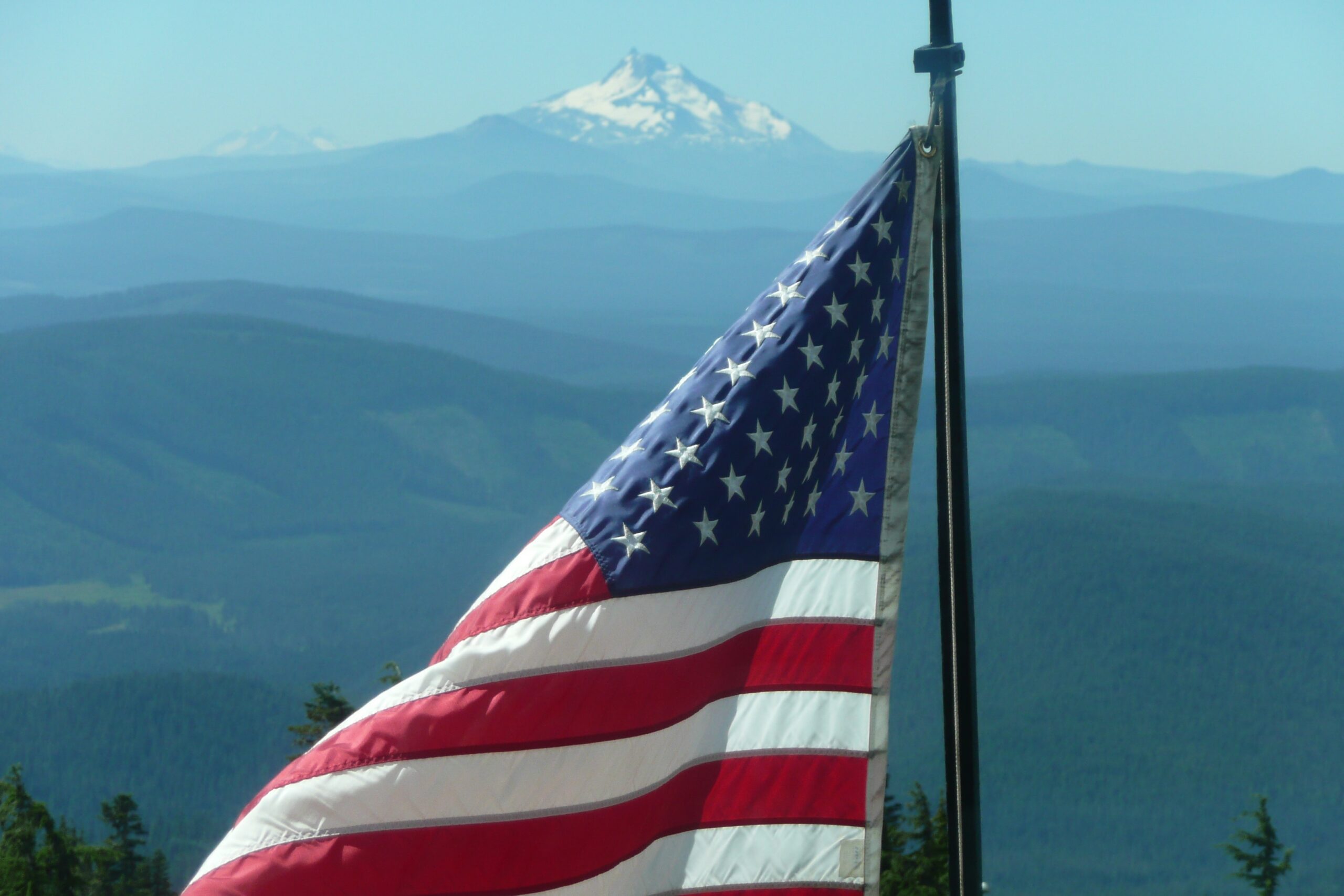 American flag waving at sunrise over mountain background , symbolizing God's blessing, faith, freedom, hope, and prayer for America.