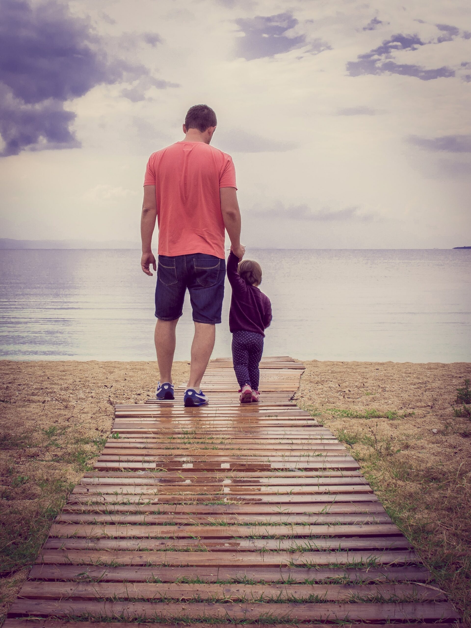 Father holding child's hand outdoors symbolizing God’s Love for us.