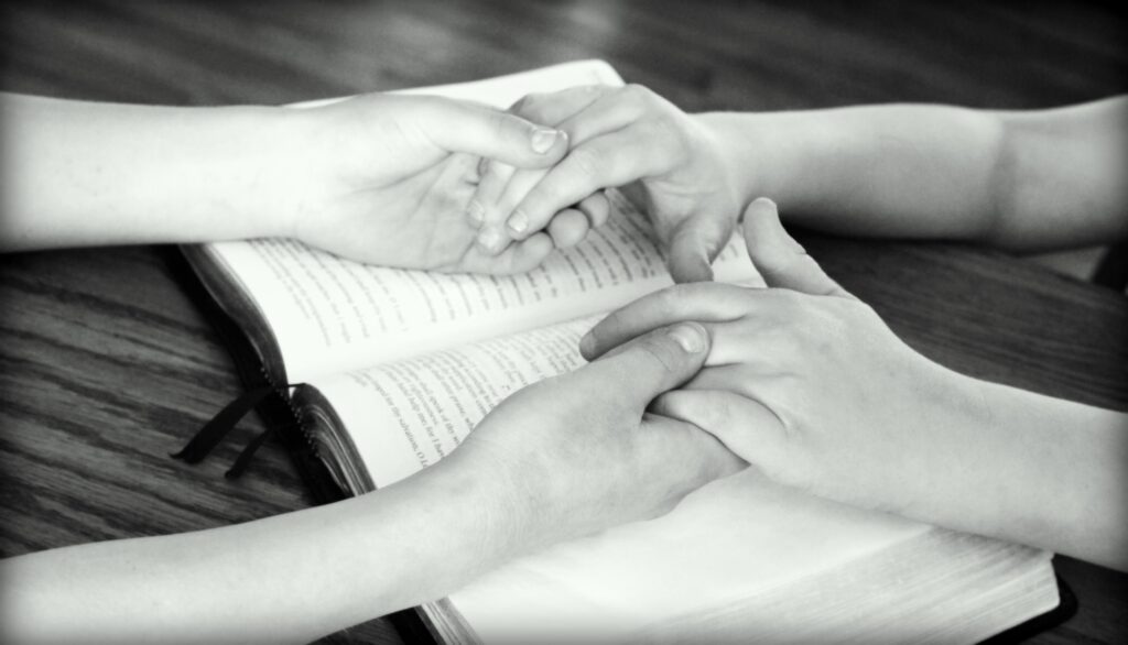 Person encouraging a friend with affirming words across an open Bible