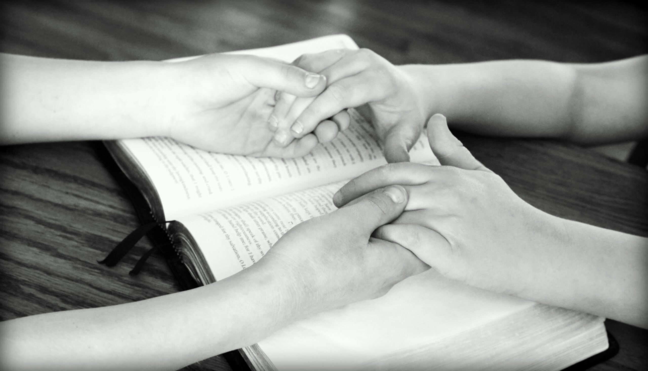 Person encouraging a friend with affirming words across an open Bible