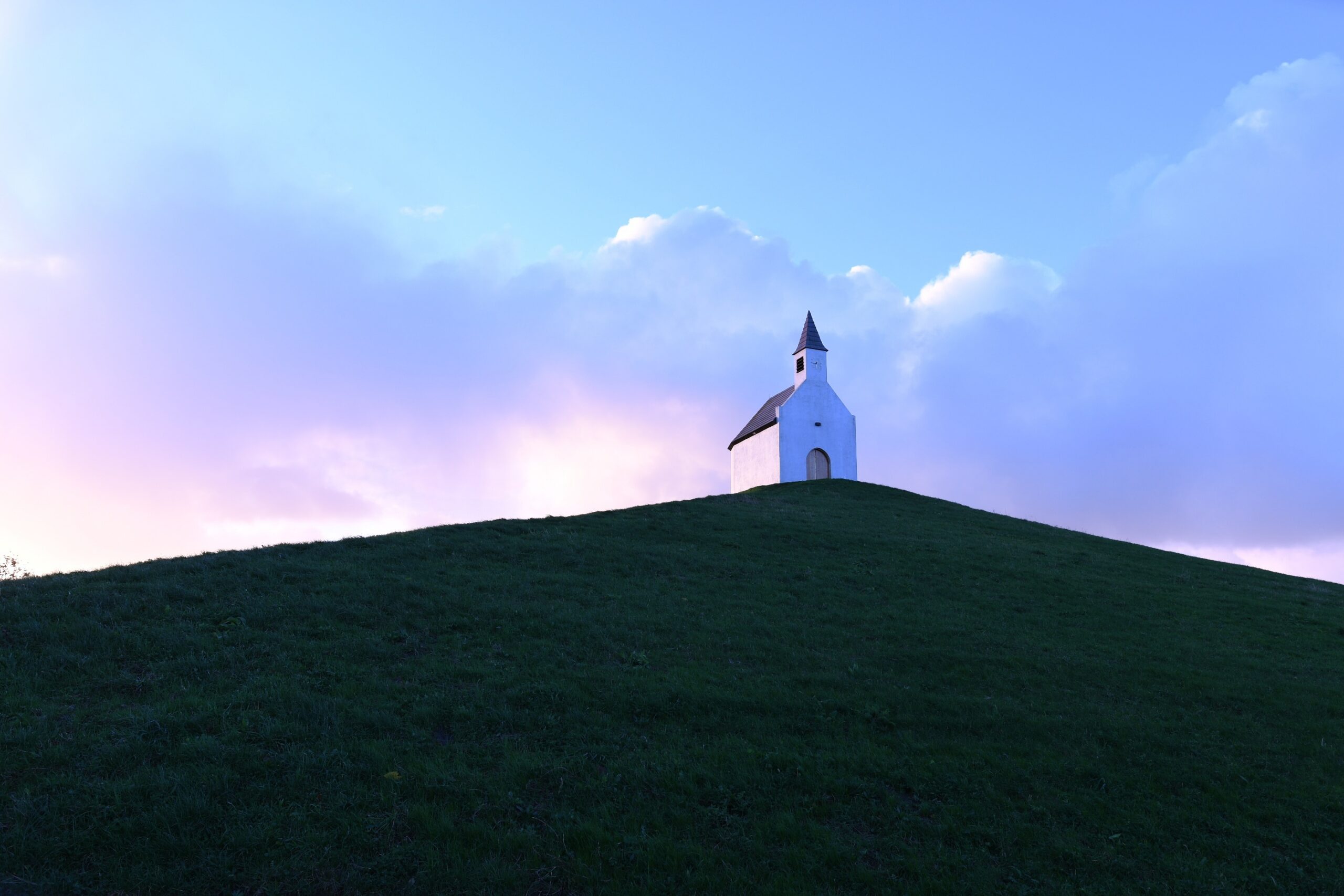 Small country church on a hilltop overlooking a lake at sunrise, illustrating the call to seek higher ground with God