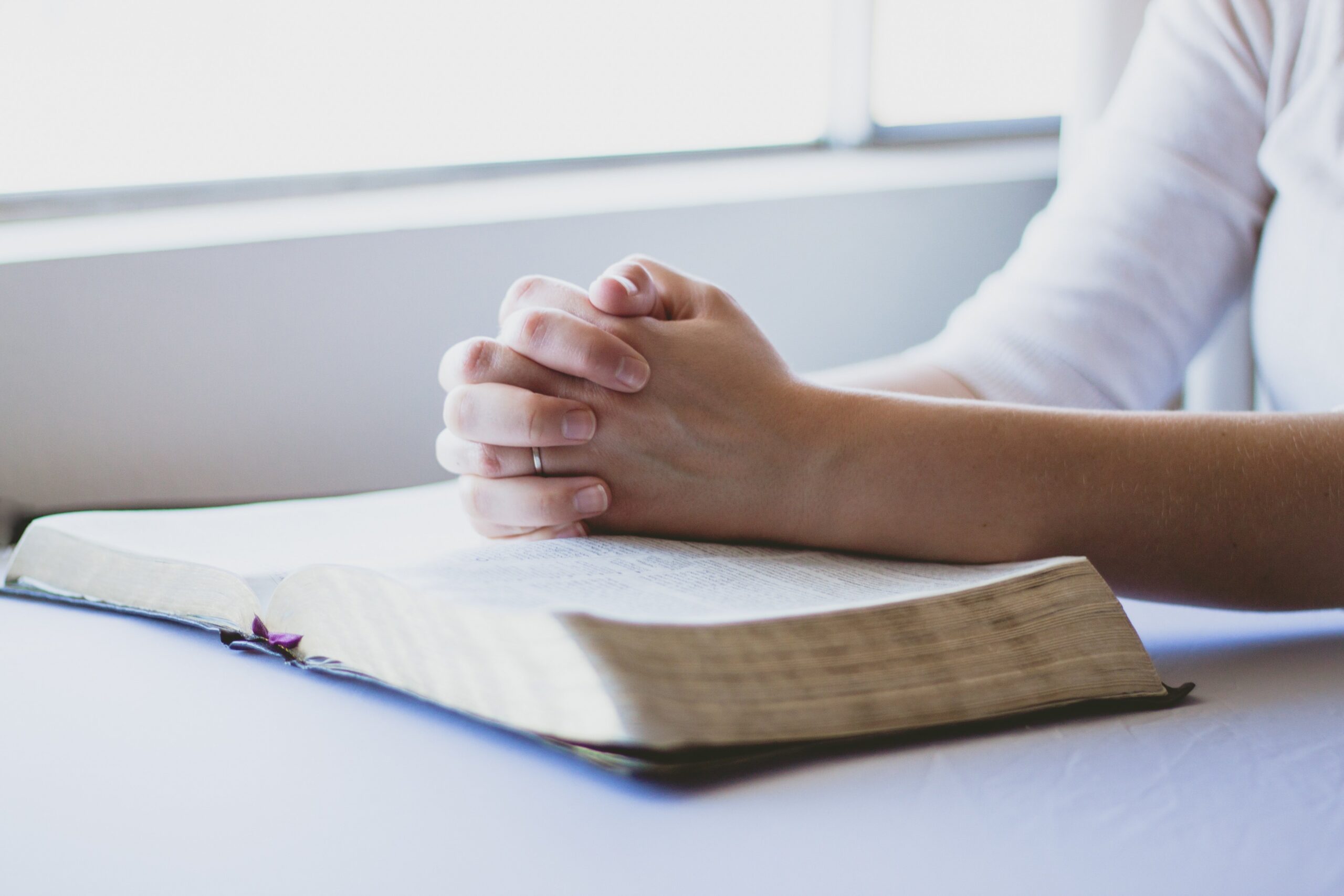 Sunlight streaming through a hospital window onto folded hands in prayer, a reminder of the miracles all around us